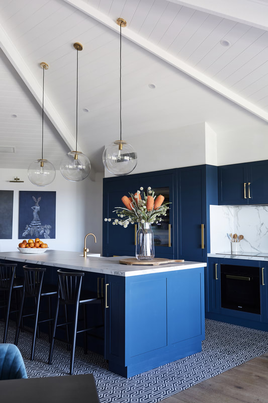 A deep navy kitchen with marble splashback and brass handles