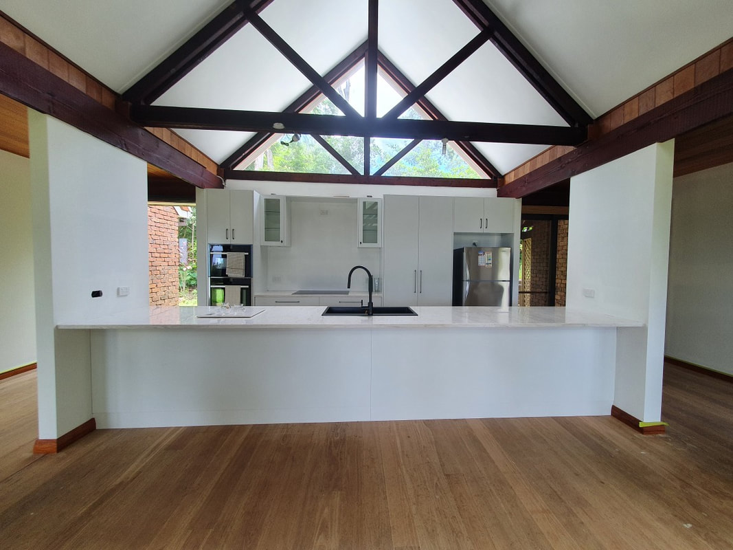 A kitchen under a cathedral ceiling with exposed timber trusses