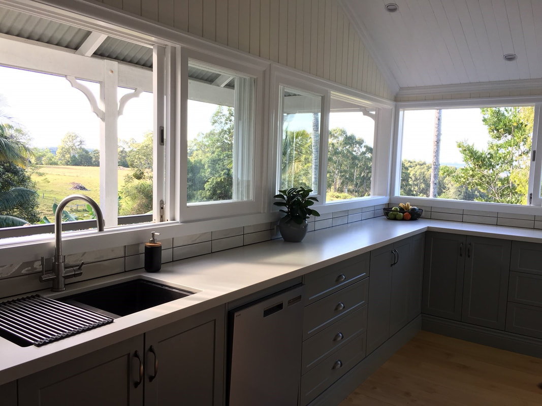 A grey kitchen with a stone benchtop and a garden outlook